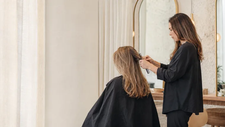 Friseurin schneidet einer Kundin die Haare im hellen Salon (Konzeptstudie Studio Mira)